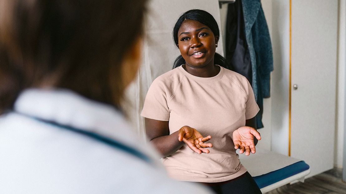 woman explaining symptoms to her doctor in a doctor's office